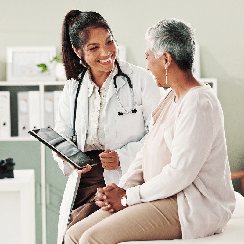 Doctor standing next to patient, showing them something on a tablet